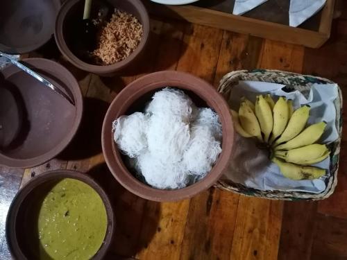 a group of bowls of food on a table with bananas at Wooden Eco Cottage in Katiyawa