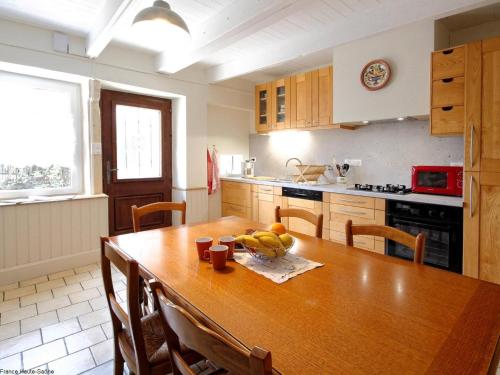 une cuisine avec une table en bois et des bananes. dans l'établissement Gîte familial rénové avec jardin au cœur de la Vallée de la Saône - FR-1-583-467, à Gourgeon