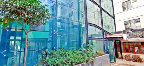 a glass building with a tree in front of it at 贵阳云舒酒店-喷水池甲秀楼店 in Guiyang