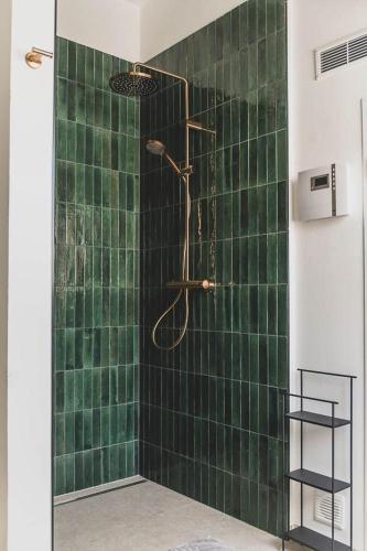 a shower with a green tiled wall in a bathroom at Appartements Brigg & Schoner in Neuharlingersiel