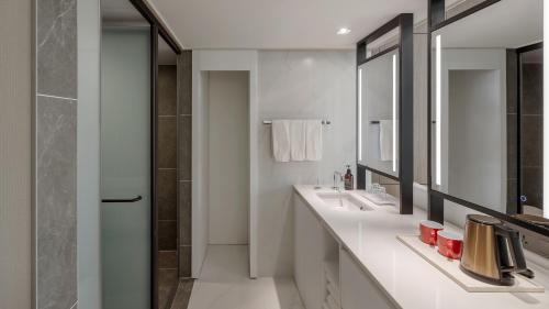 a white bathroom with two sinks and a shower at NewCZ Centum Hotel in Busan