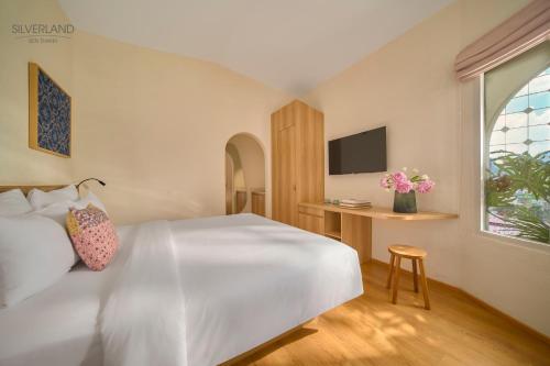 a bedroom with a large white bed and a desk at Silverland Bến Thành in Ho Chi Minh City