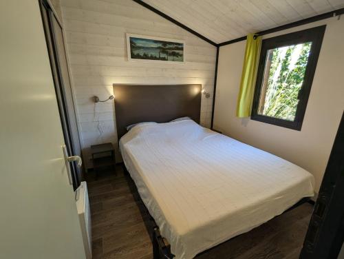 un lit dans une petite pièce avec une fenêtre dans l'établissement Cottage nature, clim, piscine, à Solliès-Toucas