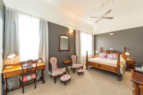 Rutland Arms Inn في وانغانوي: غرفة نوم بسرير وكراسي ومكتب