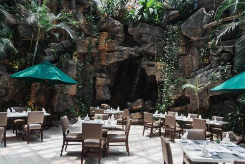 a restaurant with tables and chairs in front of a stone wall at Clarion Suites Guatemala City in Guatemala