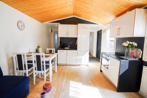 a kitchen and living room with white cabinets and a table at Mobilheim 3 in Lohmen