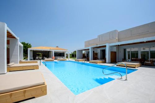 a swimming pool with chairs and a building at Blue Summer Luxury Suites in Kourouta