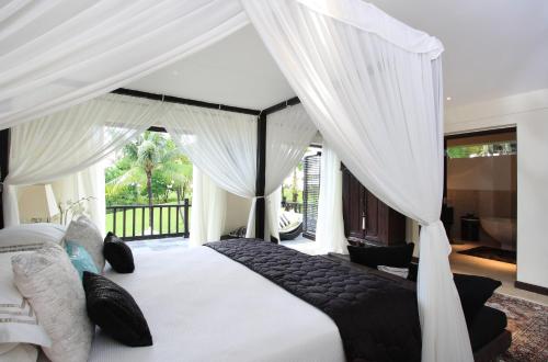 a bedroom with a large white bed with curtains at Villa Arjuna in Tanah Lot