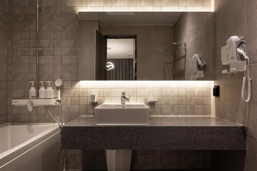 Un baño con lavabo, espejo y bañera. en 21 Heritage Hotel, en Wonju