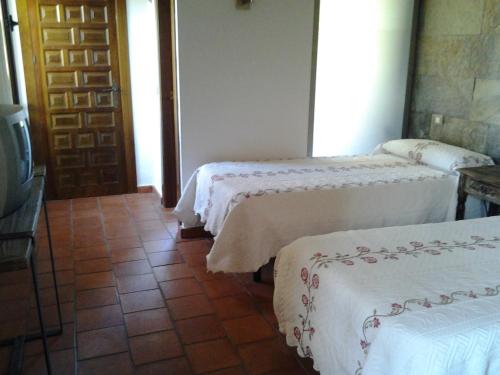 a room with three beds with white sheets and a door at Casa Rural Hidalgo in Ciudad Real