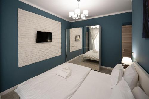 a bedroom with a white bed and a blue wall at Ozone Apartment Spa & Pool Beach Resort in Mamaia