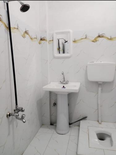 a white bathroom with a sink and a toilet at Ali Hotel in Kārandūkai