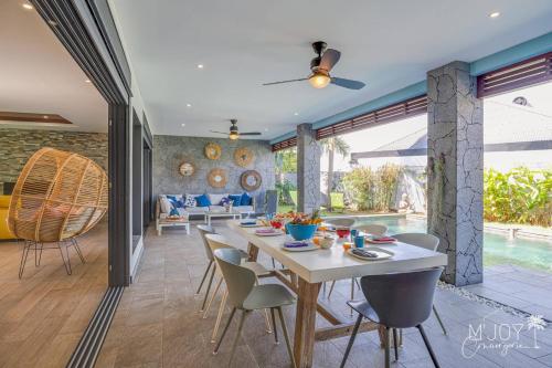 a dining room and living room with a table and chairs at TY KAZ PARADIS, villa avec piscine pleine de charme in Ravine des Cabris