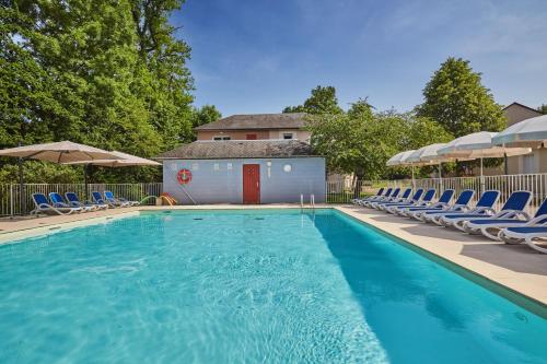une piscine avec des chaises et un bâtiment dans l'établissement Résidence Odalys Le Hameau du Lac, à Rignac