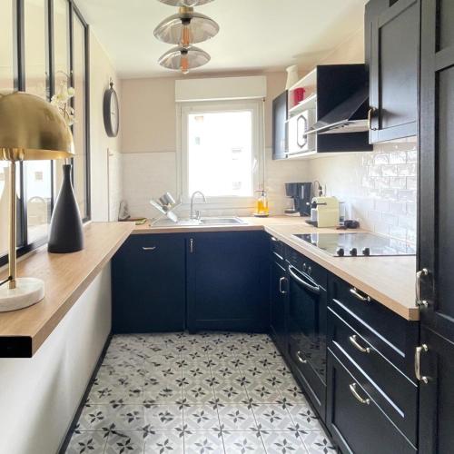 une cuisine avec des armoires noires et un tapis de cuisine dans l'établissement Luxury Appartement Disneyland, à Magny-le-Hongre