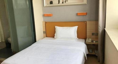 a bedroom with a bed with white sheets and an orange headboard at 7 Days Premium Zhuhai Gongbei Light Railway Branch in Zhuhai