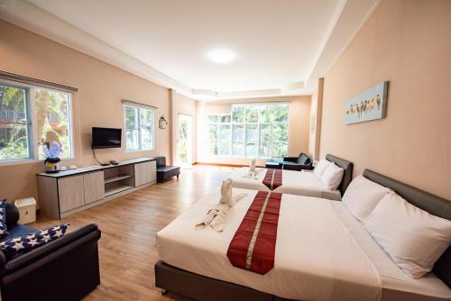 a hotel room with two beds and a tv at Baansuan Aokhai Beach Resort in Mae Pim