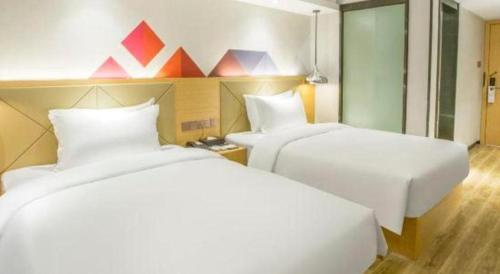 two beds in a hotel room with colorful triangles on the wall at Borrman Hotel Zhuhai Gongbei Port Fuhuali Light Rail in Zhuhai