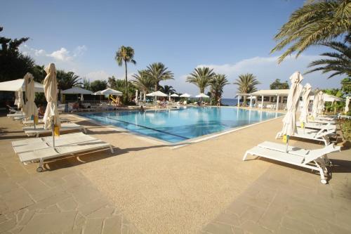 a large swimming pool with lounge chairs and umbrellas at Crystal Springs Beach Hotel in Protaras
