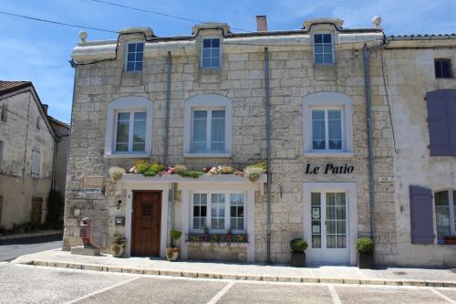 um velho edifício de pedra com um sinal para a ricota em Le Patio Chambres et Tables d'Hôtes em La Tour-Blanche