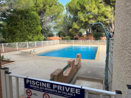 une piscine avec un panneau en face d'une clôture dans l'établissement appartement 50m2 village vacances, à Arles