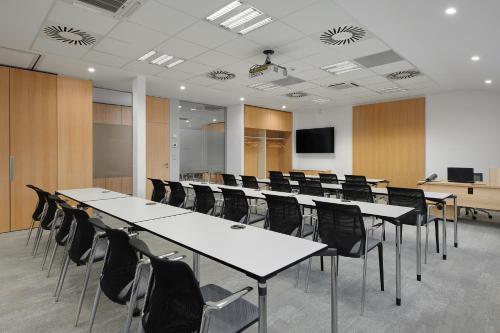 a conference room with white tables and black chairs at Hotel Osvit in Mladá Boleslav
