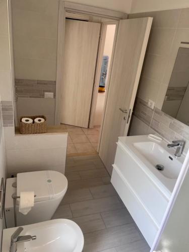 a white bathroom with a toilet and a sink at Allegracore Rental House in Catania