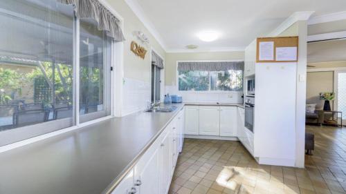 a kitchen with white cabinets and a large window at Bribie Beach House, Waterfront directly across the road - Solander Esp, Banksia Beach in Old Bribie