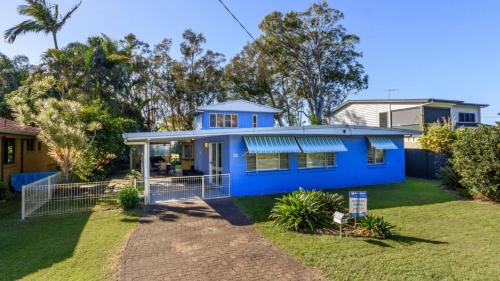 a blue house in the middle of a yard at Bribie Beach House, Waterfront directly across the road - Solander Esp, Banksia Beach in Old Bribie