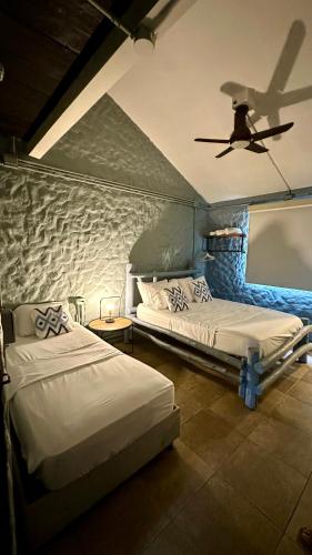 two beds in a room with a ceiling fan at Hotel Las Marias by Croma in Palomino