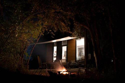 a house with a fire in front of it at night at Hill Creek Tiny House 3 by Tiny Away in Perwillowen