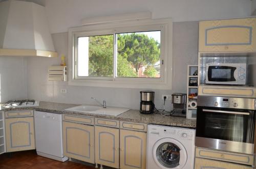 a kitchen with a sink and a washing machine at Residence de tourisme Le clos des Vendanges in Moriani Plage