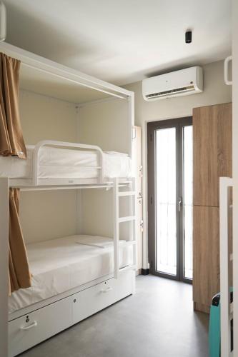 a room with two bunk beds and a window at Sweet Sevilla Hostel in Seville
