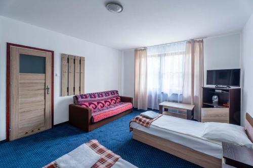a hotel room with two beds and a couch at Pensjonat Pod Lwem in Niechorze