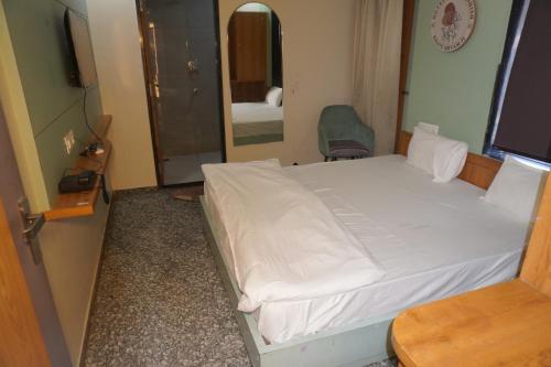 a bedroom with a white bed and a mirror at Hotel Dwarkadhish in Khātu
