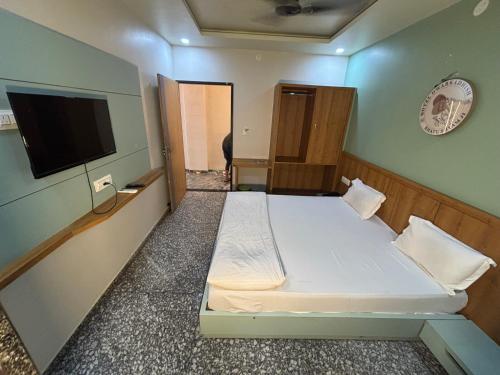 a small room with a bed and a flat screen tv at Hotel Dwarkadhish in Khātu