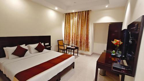 a hotel room with a bed and a desk and a window at Alps Residency - A Bergamont Hotel, Krishnagiri in Krishnagiri
