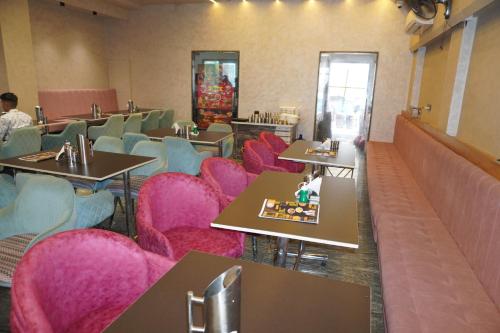 a dining room with pink chairs and tables at Hotel Dwarkadhish in Khātu