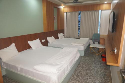 two beds in a room with a tv and a chair at Hotel Dwarkadhish in Khātu