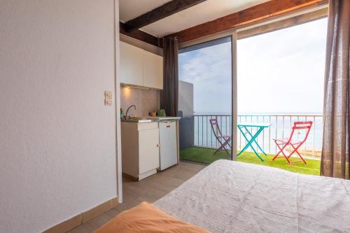 une pièce avec une cuisine et un balcon avec des chaises dans l'établissement Les Jeux de Boules 6, au Pradet