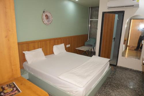 a small bedroom with a white bed and a chair at Hotel Dwarkadhish in Khātu