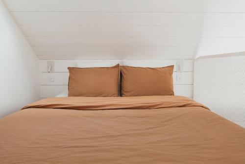 - un lit dans une chambre blanche avec 2 oreillers dans l'établissement Tiny House d'exception au bord de mer, à La Bernerie-en-Retz