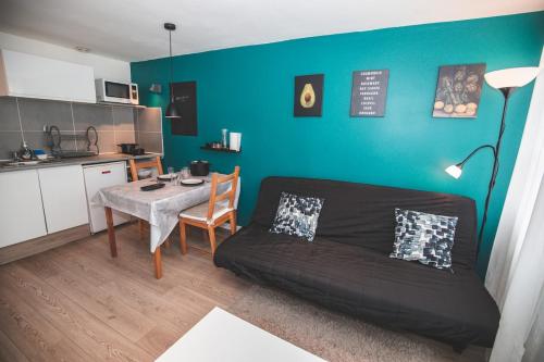 un salon avec un canapé et une table et une cuisine dans l'établissement Studio moderne tout équipé au pied des monuments, au Puy-en-Velay