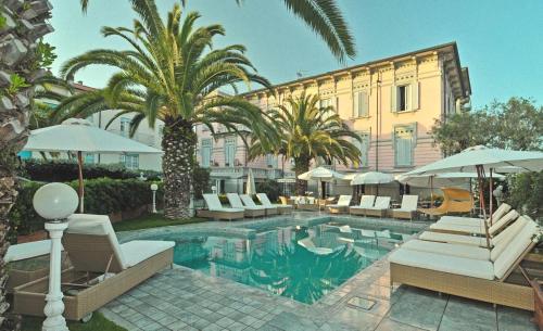 a pool with chairs and umbrellas next to a building at Hotel Europa in Lido di Camaiore