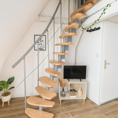 un escalier en colimaçon en bois dans une pièce blanche avec une télévision dans l'établissement Studio Cosy ambiance Tiny House, à Angers