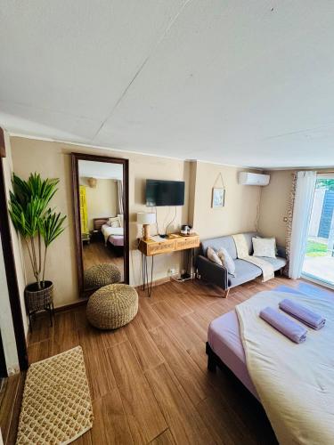 a bedroom with a bed and a couch and a mirror at L'Écrin de Marie-Paule - Proche Aéroport in Saint-Denis