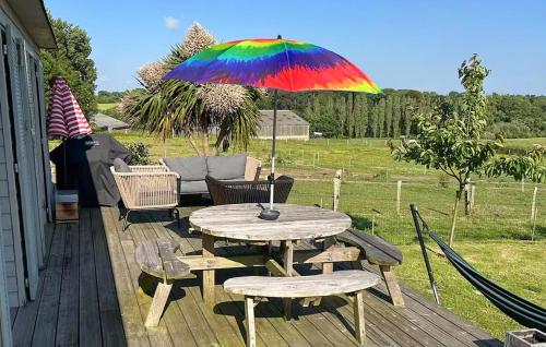 a table and chairs with a colorful umbrella on a deck at 5 Bedroom Beautiful Home In Taulé in Taulé