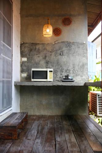 a kitchen with a microwave and a wooden floor at Baannoi Nornmuan retreat vacation rental & workshop Chiang Mai in Chiang Mai