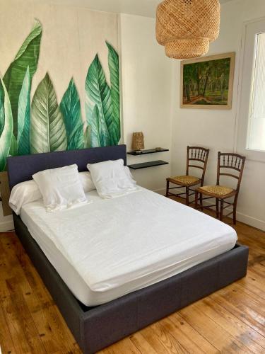 un lit dans une pièce avec des chaises et un mur avec des feuilles dans l'établissement La Maison Flores, à Coulounieix-Chamiers