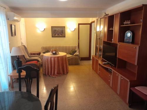 a living room with a table and a television at Alojamiento El Sevillano in Cullera
